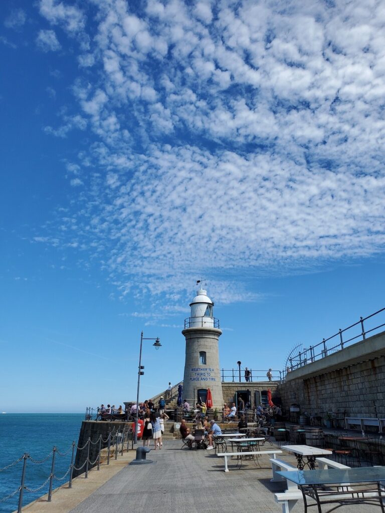 A picture of Folkstone Harbour Arm light house, blue sky by the sea