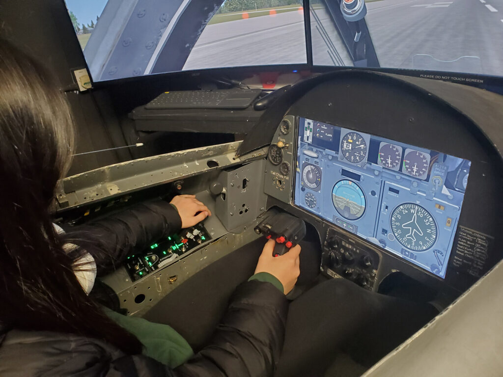 Visitor piloting a jet flight simulator at Farnborough Air Sciences Trust museum.